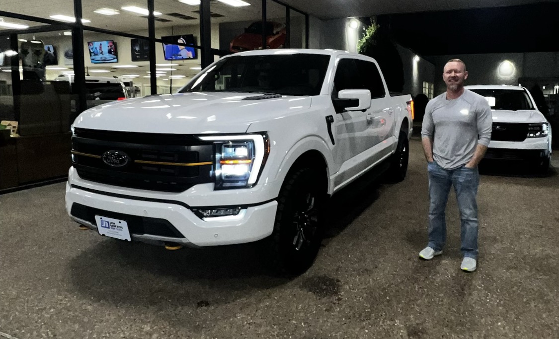 Customer taking delivery of a white Ford F-150 at night