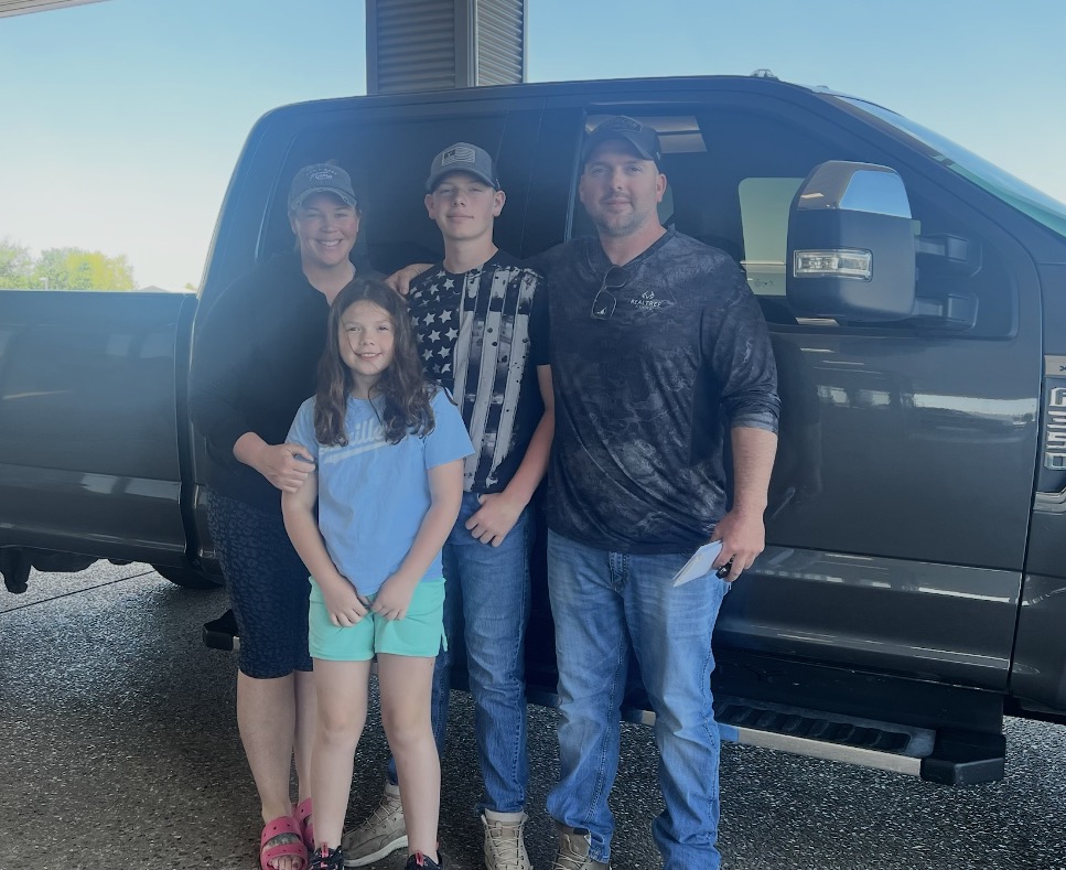Family of four posing with their new Ford Super Duty truck