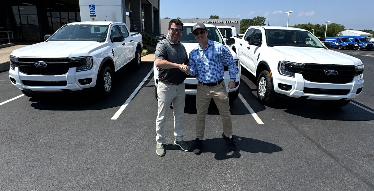 Rylan Beebe shaking hands with a customer between two new Ford Rangers