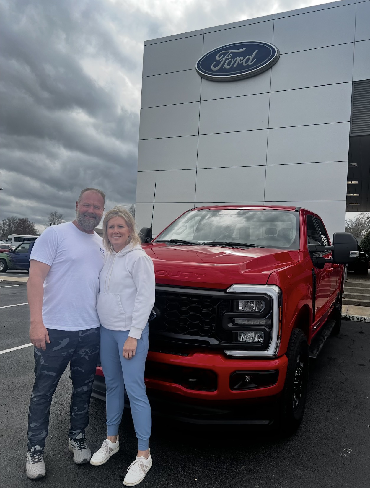 Two customers in front of a red Ford Super Duty truck at the dealership